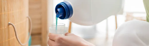 Cropped view of woman pouring softener in laundry room, banner — Foto stock