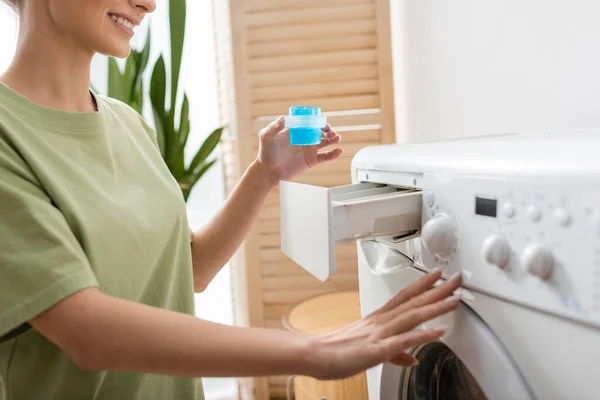 Cropped view of smiling woman holding liquid cleaner near washing machine at home — Foto stock