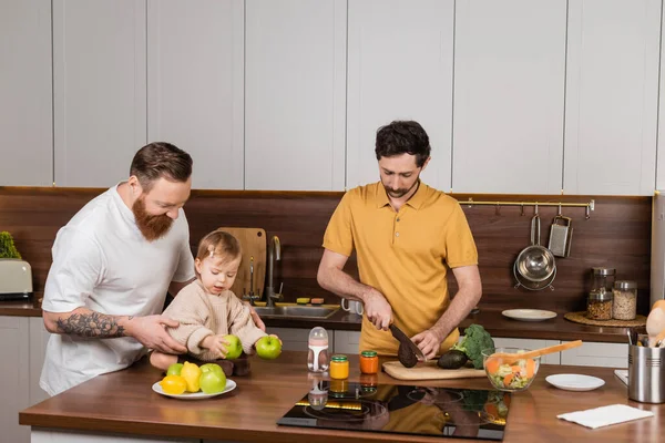 Гей-чоловік готує біля партнера і дочки малюка на кухні — стокове фото