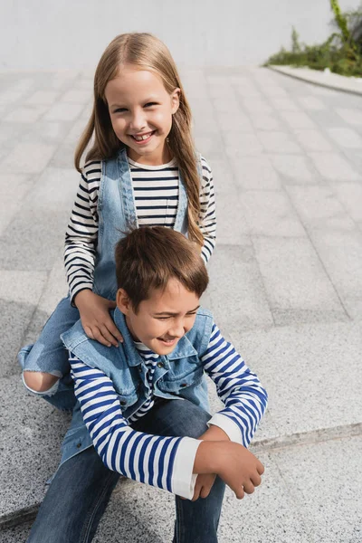 Pleased girl in stylish clothes leaning on shoulders of well dressed boy — Photo de stock