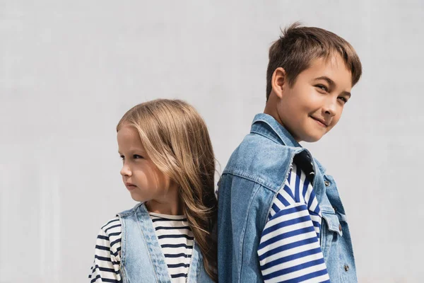 Gut gekleidete Jungen und Mädchen in Jeans-Outfits schauen im Freien in die Kamera — Stockfoto