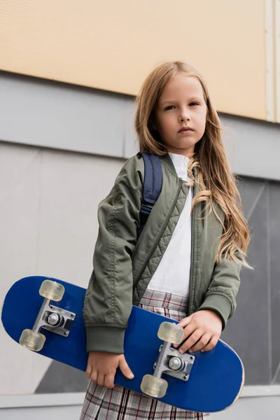 Stylish preteen girl in bomber jacket holding penny board near mall — Foto stock