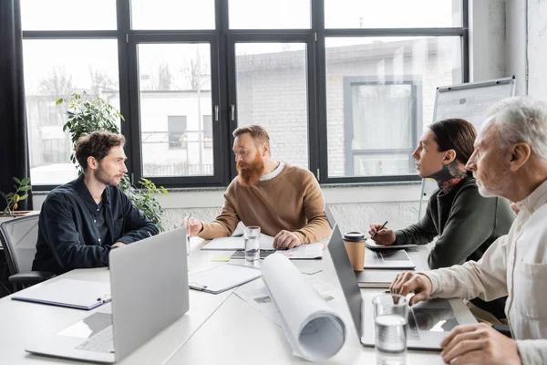 Empresário conversando com colegas com laptops durante o treinamento no escritório — Fotografia de Stock
