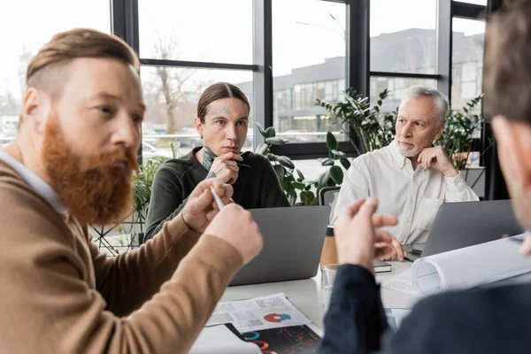 Geschäftsleute sitzen bei Besprechungen im Büro neben Laptops und Papieren — Stockfoto