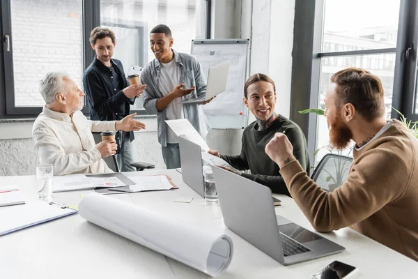 Interrassische Geschäftsleute diskutieren Projekt und Nutzung von Laptops bei Treffen im Büro — Stockfoto