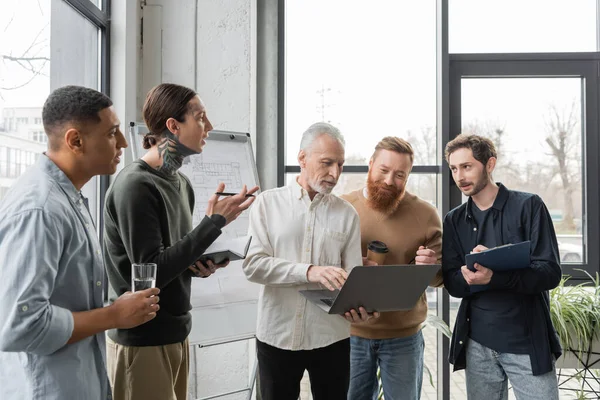 Multiethnic business people talking during training near flip chart in office — Stock Photo