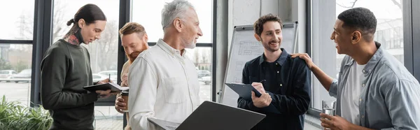 Lächelnde interrassische Geschäftsleute im Gespräch während eines Treffens im Büro, Banner — Stockfoto
