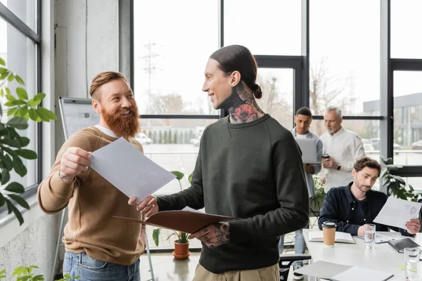 Smiling tattooed business people working on project in office — Stock Photo