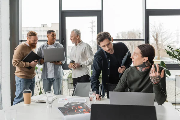 Empresários com prancheta e laptop conversando durante reunião no escritório — Fotografia de Stock