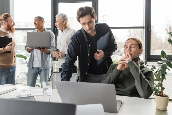 Сфокусированные бизнесмены с буфером обмена с помощью ноутбука во время встречи в офисе — стоковое фото