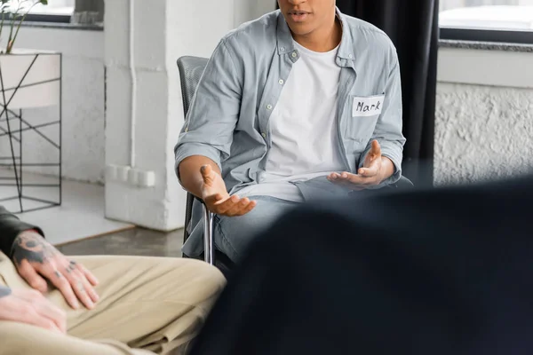 Обрезанный вид африканского американца с алкогольной зависимостью разговаривающего во время терапии в реабилитационном центре — стоковое фото