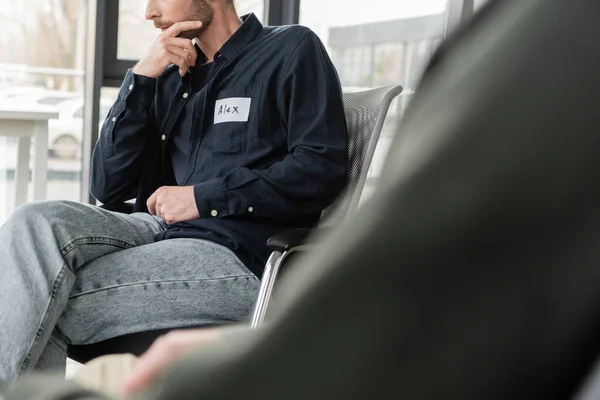 Vista cortada do homem com dependência de álcool sentado na cadeira no centro de reabilitação — Fotografia de Stock