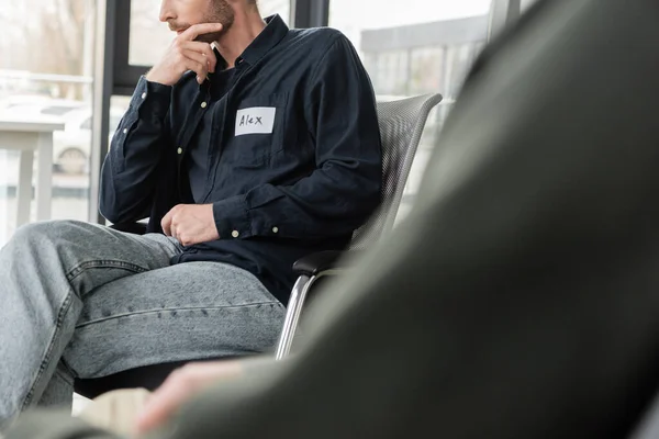 Vue recadrée de l'homme avec dépendance à l'alcool assis sur la chaise dans le centre de réadaptation — Photo de stock