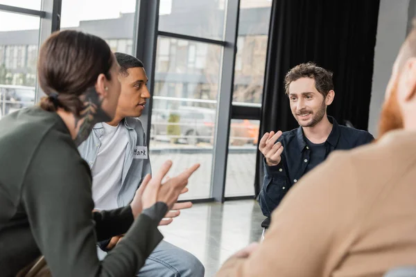 Interracial people with alcohol addiction talking during group therapy in rehab center — Stock Photo