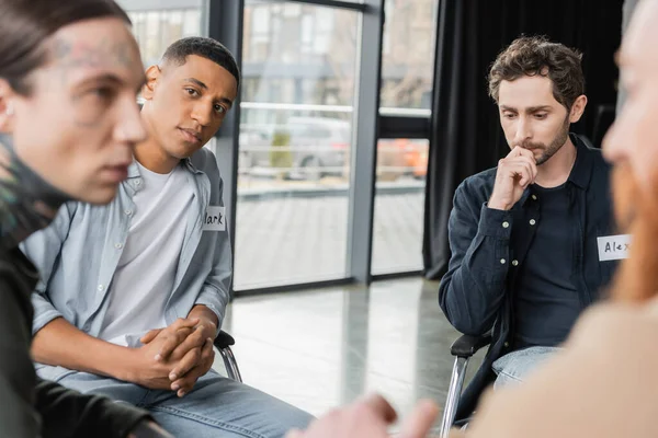 Interracial people with name stickers talking during alcoholics meeting in rehab center — Stock Photo