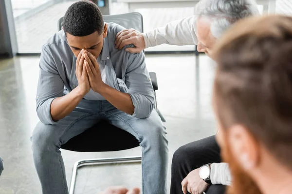 Uomo africano americano depresso seduto in gruppo durante l'incontro degli alcolisti nel centro di riabilitazione — Foto stock