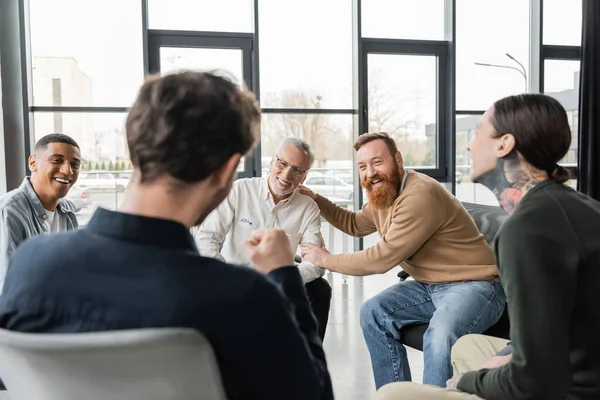 Cheerful interracial group of people with alcohol addiction talking in rehab center — Stock Photo