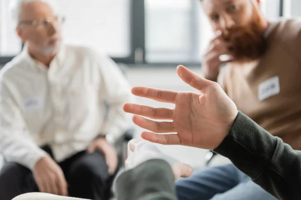Man sitting near blurred group during alcoholics meeting in rehab center — Stock Photo