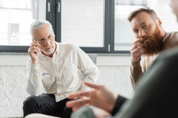 People looking at blurred man during alcoholics meeting in rehab center — Stock Photo