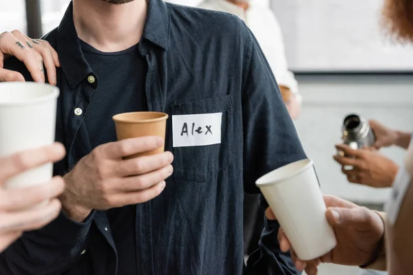 Cropped view of people holding paper cups during alcoholics meeting in recovery center — Photo de stock