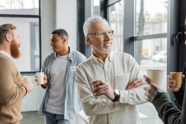 Lächelnder älterer Mann mit Pappbecher bei Alkoholikertreffen im Erholungszentrum — Stockfoto