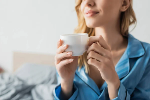 Vue recadrée de jeune femme heureuse en pyjama bleu tenant tasse de café — Photo de stock