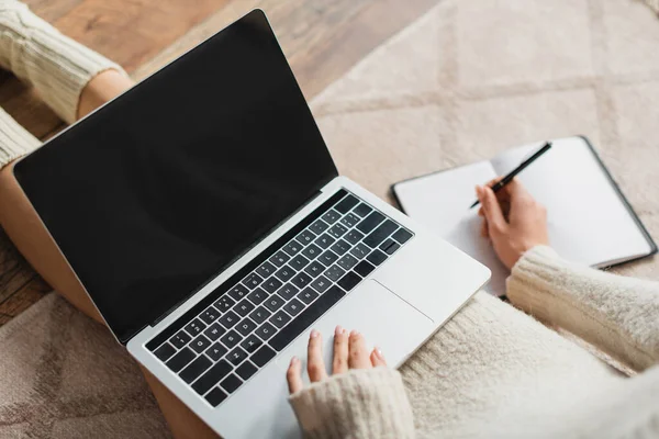 Vista ritagliata di freelance prendere appunti su notebook durante l'utilizzo di laptop con schermo vuoto — Foto stock