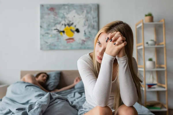 Стурбована молода жінка сидить на ліжку після однієї ночі стоїть з незнайомцем — стокове фото