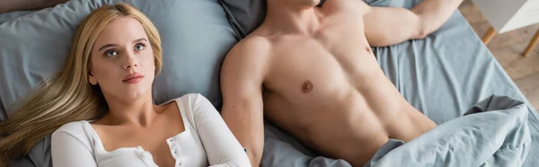 Высокий угол зрения смущенной женщины просыпаясь с мужчиной без рубашки после одной ночи, баннер — стоковое фото