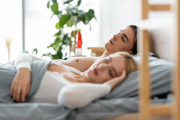 Shirtless man sleeping under blanket with blonde woman after one night stand — Stock Photo