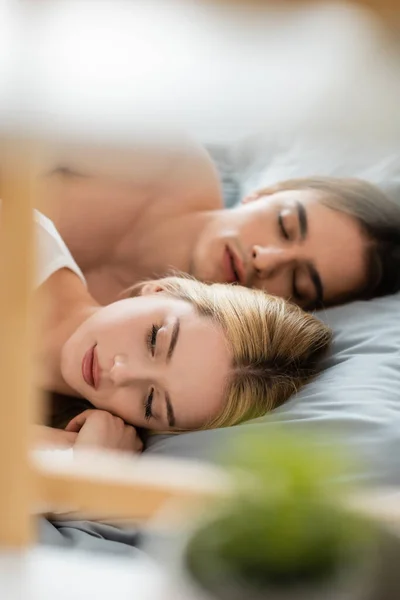 Awakened woman lying in bed with sleepy man after one night stand — Stock Photo