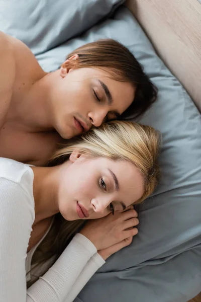 Vista superior del hombre sin camisa durmiendo con la mujer rubia después de una noche - foto de stock