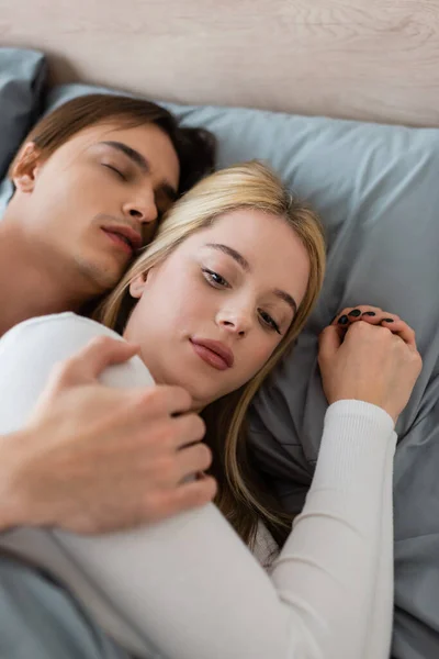 Top view of shirtless man sleeping and hugging confused woman after one night stand — Stock Photo