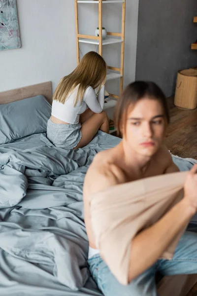 Blonde woman regretting after having one night stand with man wearing clothes on blurred foreground — Stock Photo