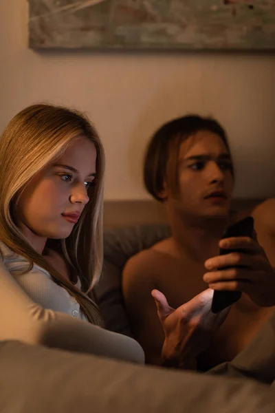 Homem sem camisa mostrando smartphone para namorada infiel no quarto — Fotografia de Stock