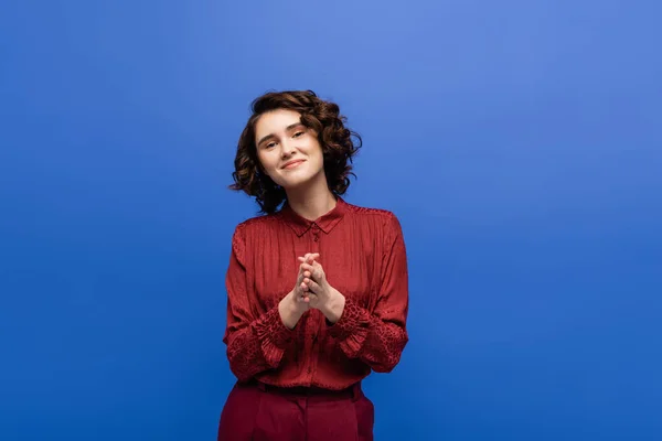 Positive language teacher with short curly hair looking at camera isolated on blue — Stock Photo