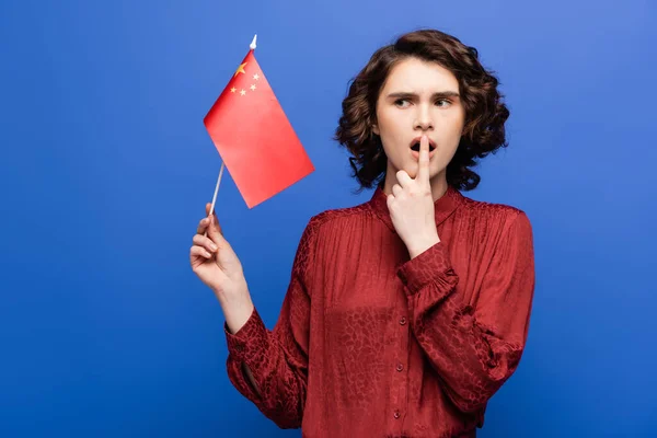 Shocked student with opened mouth holding flag of China isolated on blue — Stock Photo