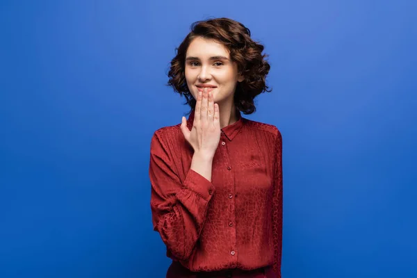 Carefree woman looking at camera and telling thank you on sign language isolated on blue — Stock Photo