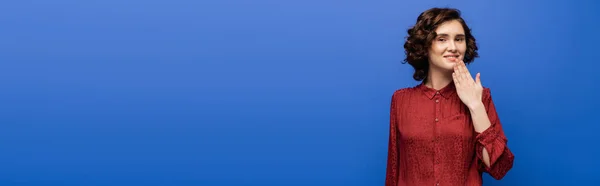 Donna allegra in camicetta rossa che ti ringrazia sul linguaggio dei segni isolato su blu, banner — Foto stock