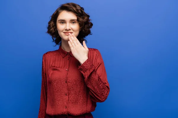 Feliz joven mujer diciendo gracias en el lenguaje de señas aislado en azul - foto de stock