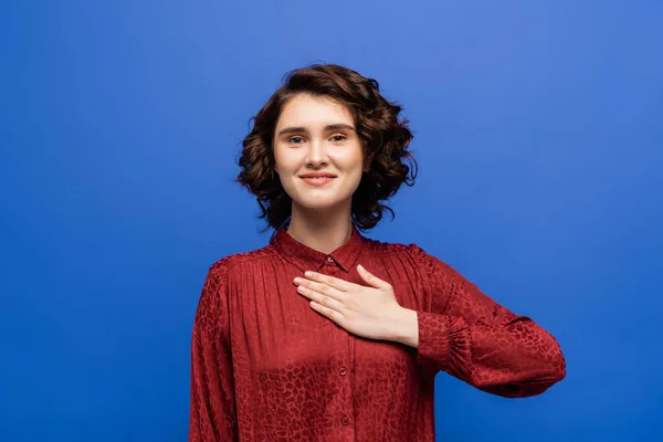 Cheerful woman looking at camera and telling please on sign language isolated on blue — Stock Photo