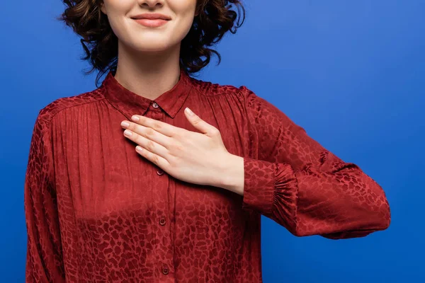 Corte vista de mulher sorridente em blusa vermelha dizendo por favor em língua de sinais isolado em azul — Fotografia de Stock