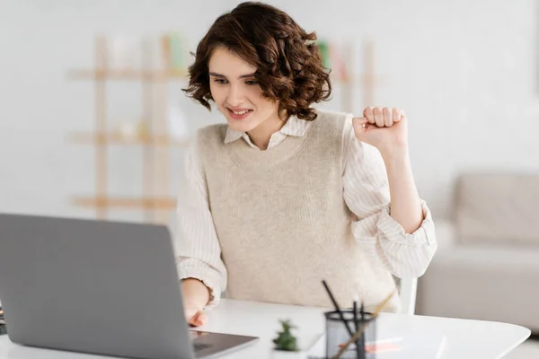 Mujer positiva enseñando cómo hablar el lenguaje de señas mientras que tiene lección en línea en el ordenador portátil - foto de stock