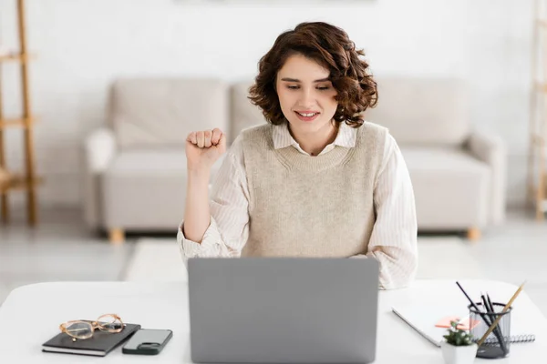Cheerful woman teaching how to speak sign language while showing clenched fist during online lesson on laptop — Stock Photo
