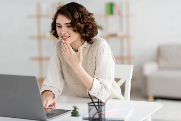 Positive teacher with curly hair showing thank you gesture during online lesson on laptop — Stock Photo