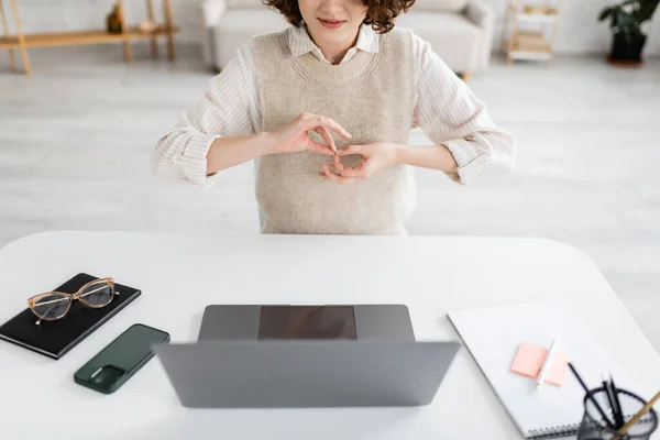 Partial view of sign language teacher showing gesture meaning interpreter near laptop and mobile phone at home — Stock Photo