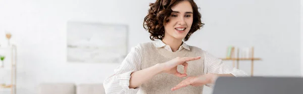 Happy teacher with curly hair showing sign language gesture during online lesson on laptop, banner — Stock Photo