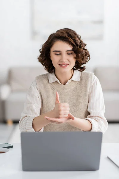 Positive teacher with curly hair showing help word on sign language during online lesson at home — Stock Photo