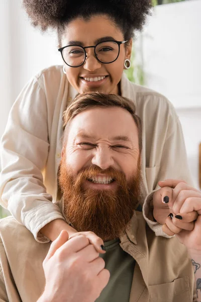 Portrait of positive african american woman holding hands of bearded boyfriend at home — Stock Photo
