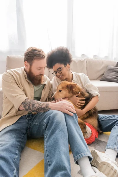 Smiling african american woman hugging handicapped dog near tattooed boyfriend at home — Stock Photo